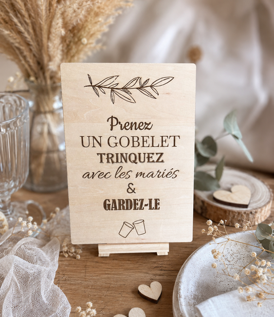 Panneau en bois gravé mariage avec inscription "Prenez un gobelet, trinquez avec les mariés et gardez-le", décoration bohème pour réception de mariage.
