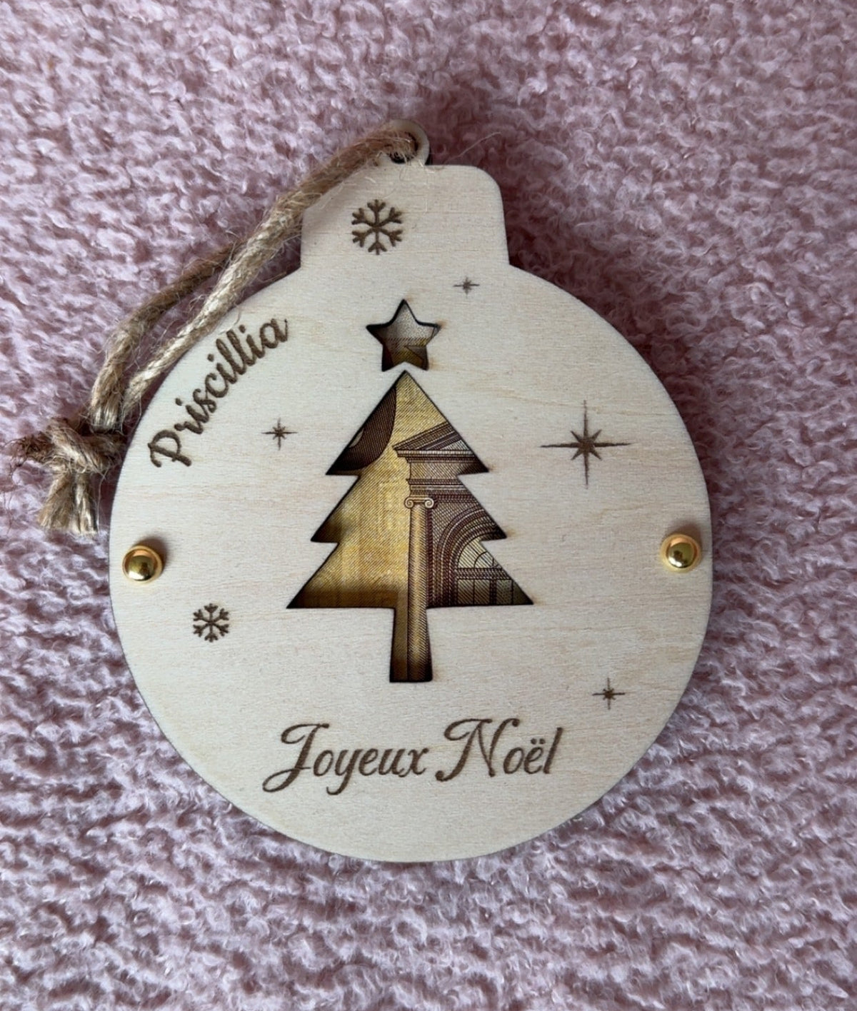 Boule de Noël en bois personnalisée «  Joyeux Noël » prénom  avec sapin et étoile découpés laissant voir un billet, flocons gravés et cordelette en jute